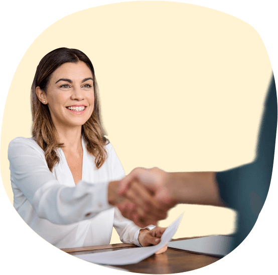 A woman shaking hands with a man in front of a yellow background.